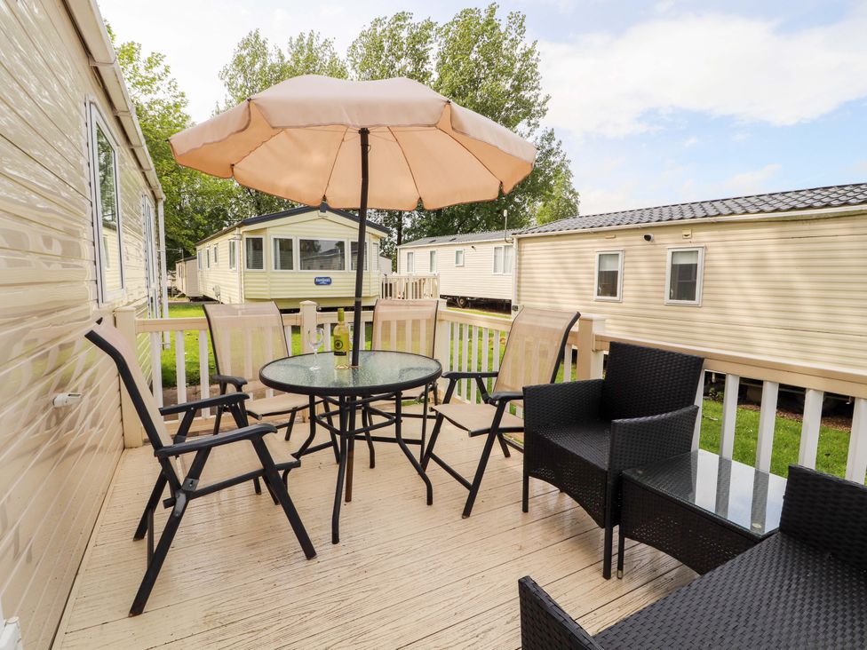 A table with chairs and an umbrella on a deck at Caravan