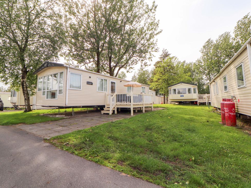 A caravan with a deck surrounded by grass and trees at Caravan in 