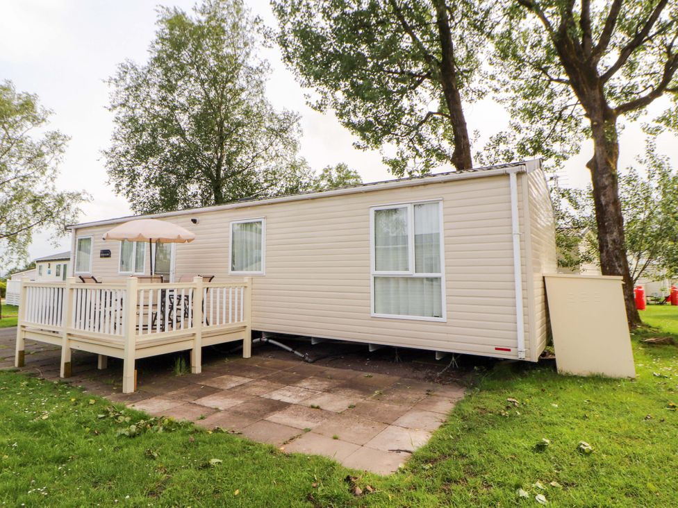 A caravan with decking and an umbrella on a patio at Caravan