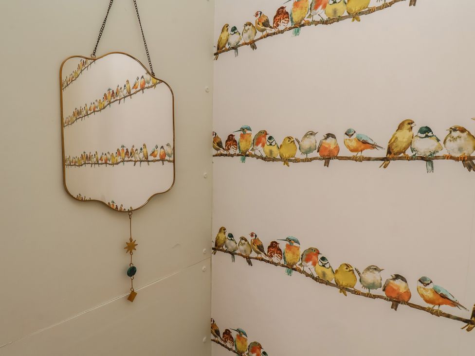 A bathroom with a bird-themed wallpaper and a mirror at 4 Studley Terrace Whitby