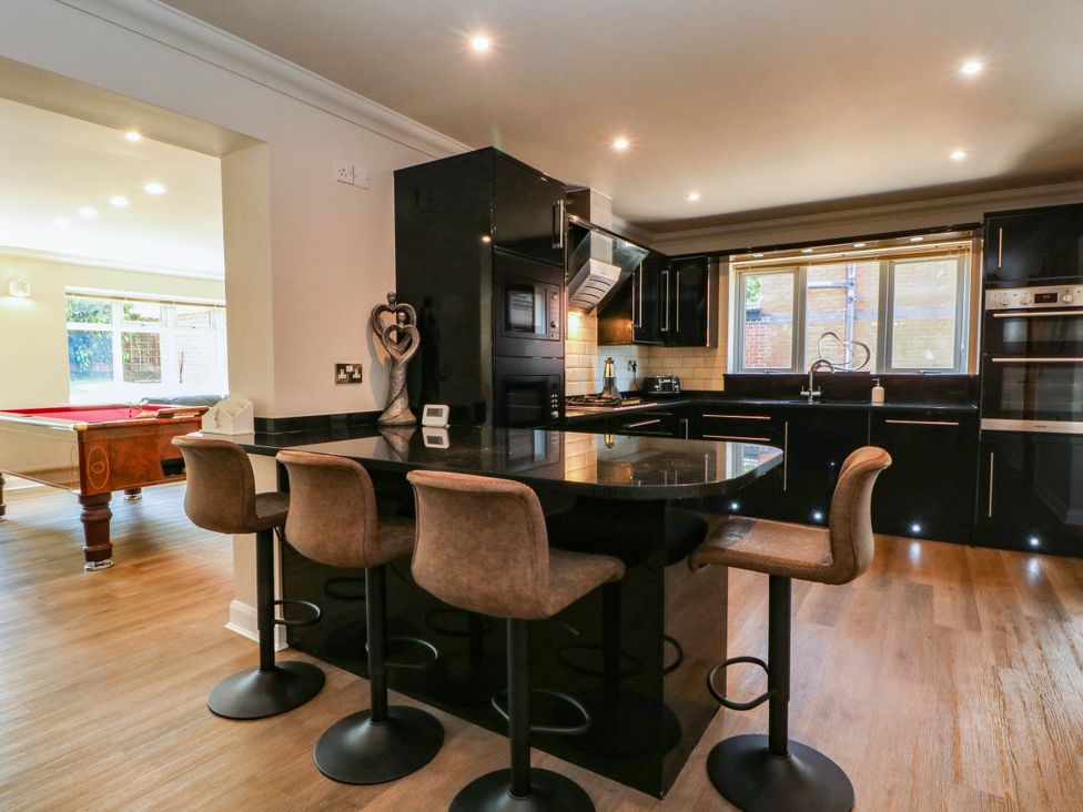 A kitchen with bar stools and appliances at The Ferns in Kirkham