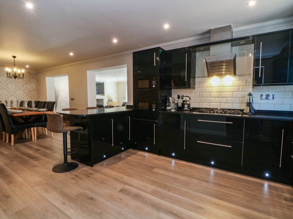 A kitchen with black cabinets and a dining area at The Ferns in Kirkham