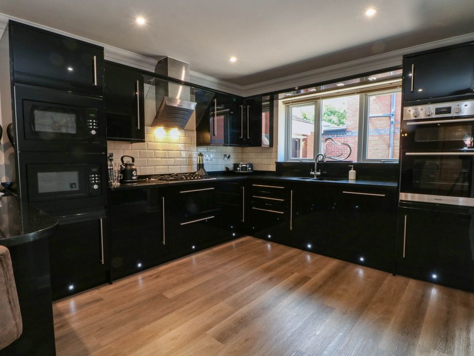 A kitchen with black cabinets and appliances at The Ferns in Kirkham