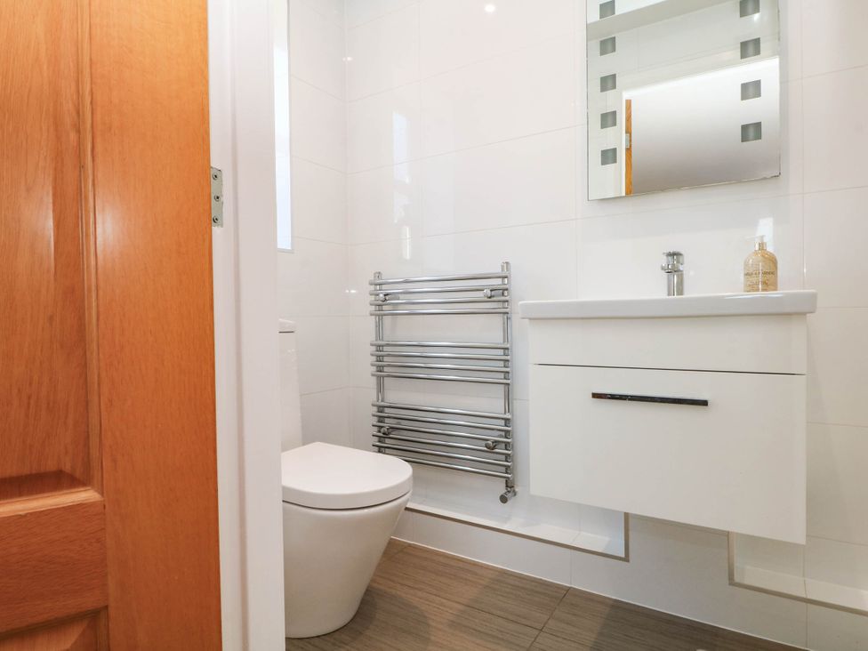 A bathroom with a toilet, sink, mirror, and towel rail at The Ferns in Kirkham
