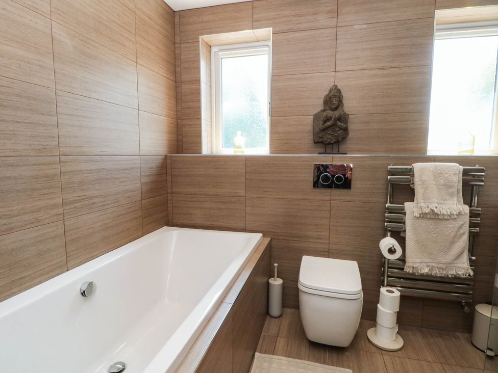 A bathroom with a bathtub, toilet, towel rack and a statue at The Ferns in Kirkham