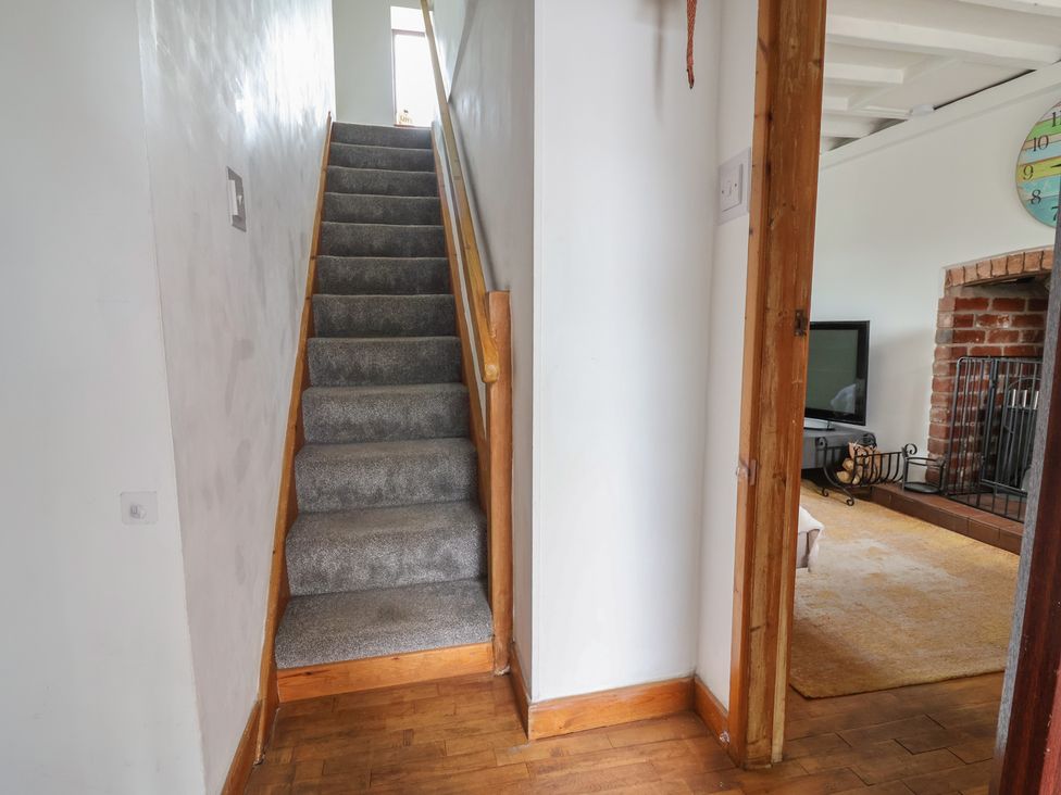 Stairs leading to upper floor with television and fireplace at Tenandeleven Cottage Denbigh