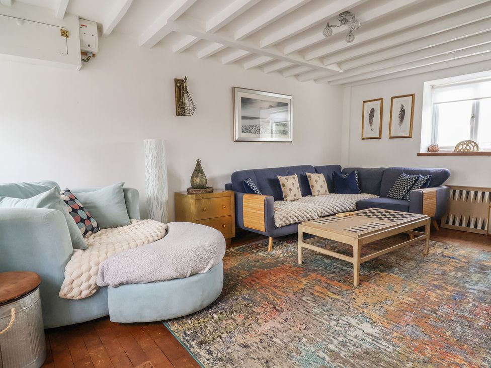 A living room with a blue sofa and wooden coffee table at Tenandeleven Cottage in Denbigh