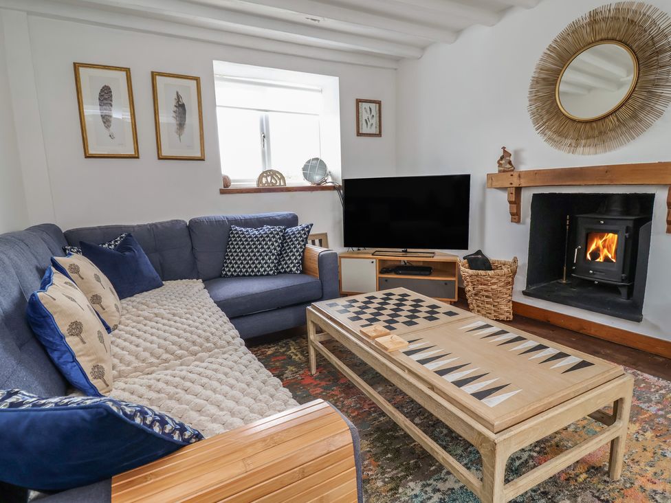 A living room with a sofa, coffee table, and television at Tenandeleven Cottage in Denbigh