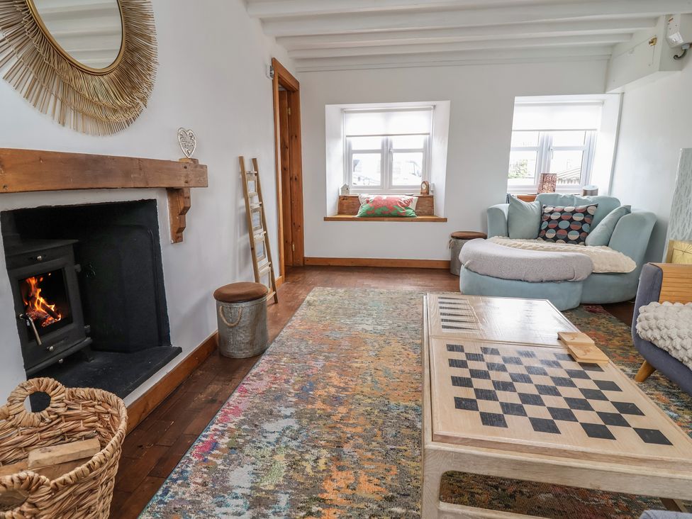 A living room with a fireplace and a sofa at Tenandeleven Cottage in Denbigh