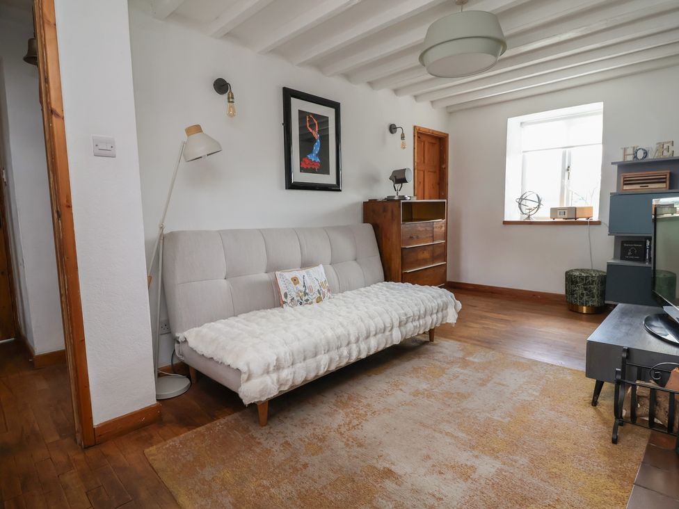A living room with a sofa and lamp at Tenandeleven Cottage in Denbigh