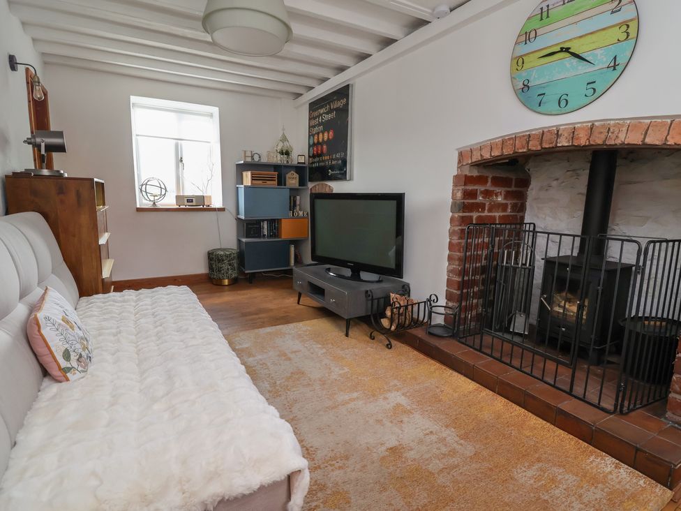 A living room with a sofa and television at Tenandeleven Cottage in Denbigh