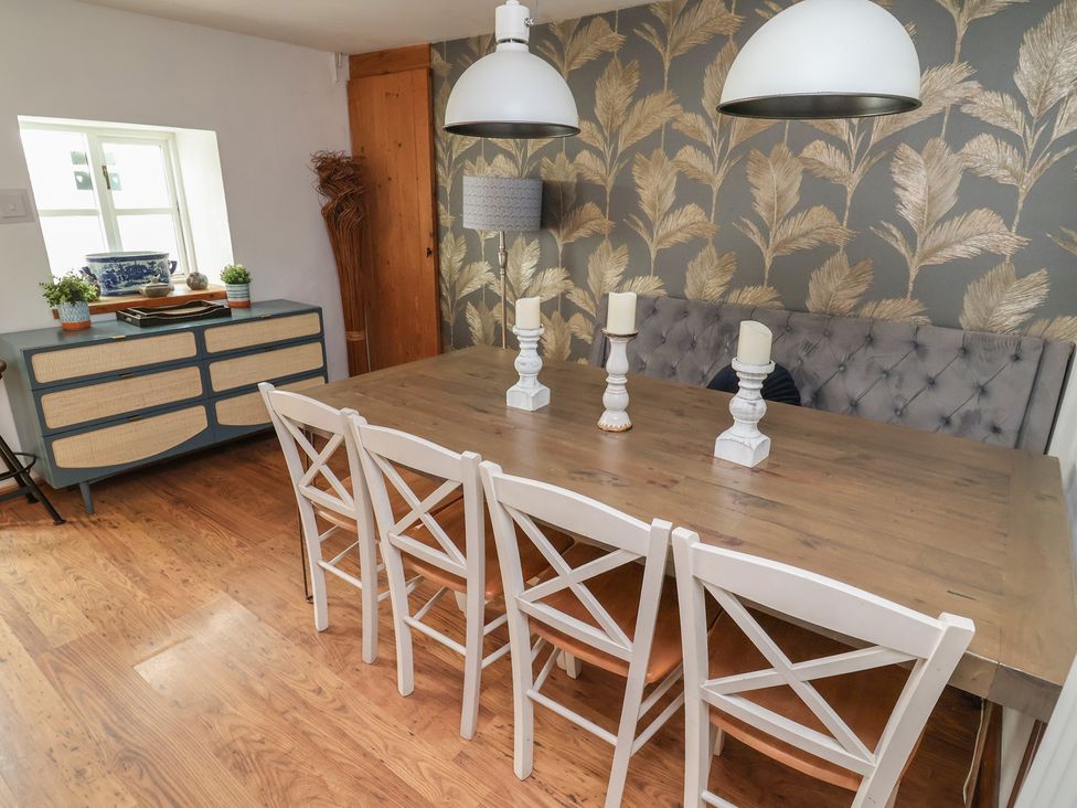 A dining room with a table and chairs at Tenandeleven Cottage in Denbigh