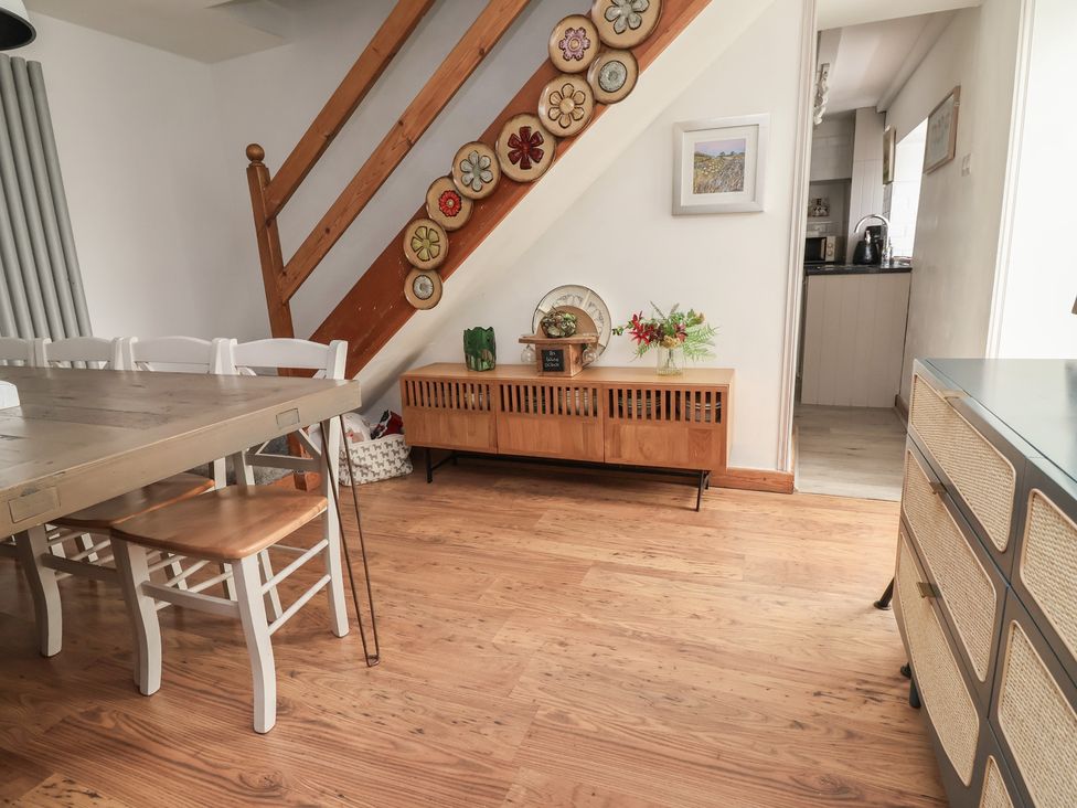 A dining room with a staircase and sideboard at Tenandeleven Cottage Denbigh