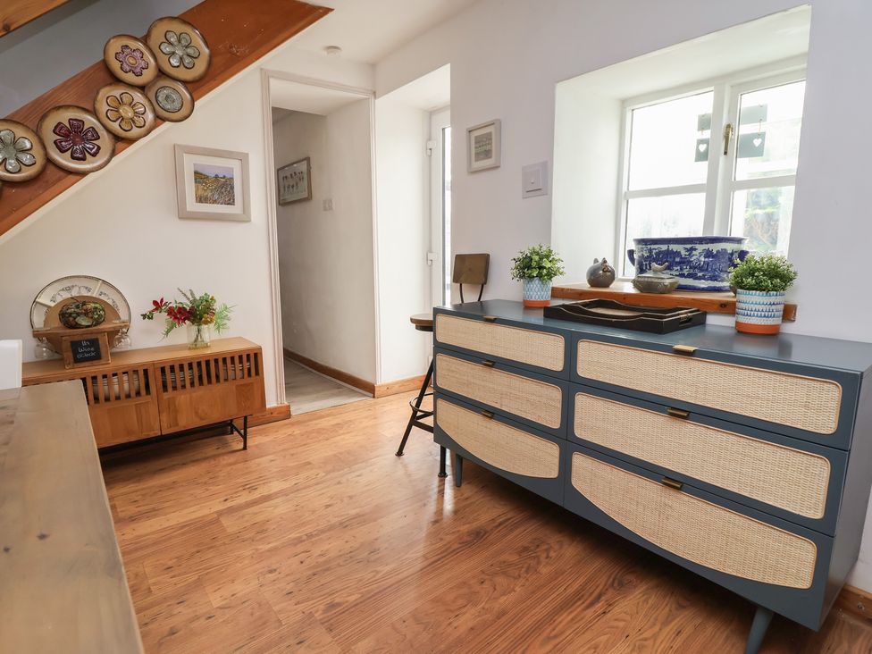 A living room with a dresser and chair at Tenandeleven Cottage in Denbigh