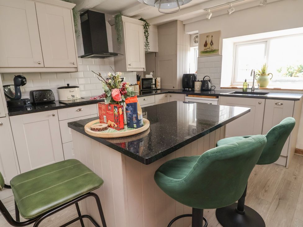 A kitchen with a black countertop and appliances at Tenandeleven Cottage in Denbigh