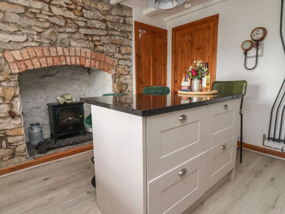 A kitchen with a fireplace and a kitchen island at Tenandeleven Cottage Denbigh