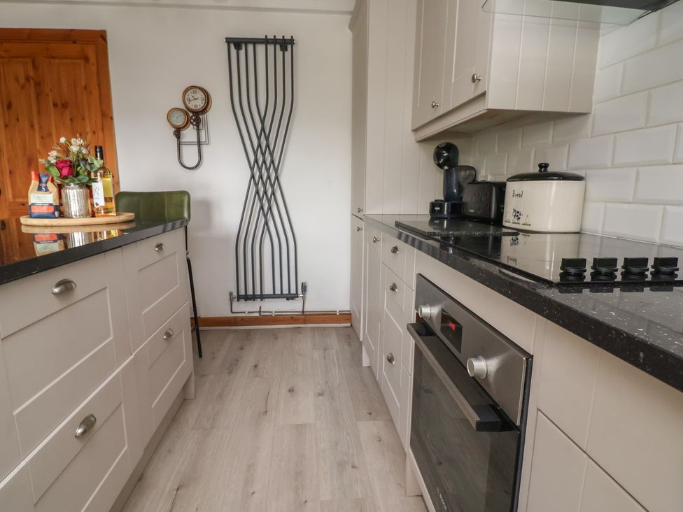 A kitchen with counters and appliances at Tenandeleven Cottage in Denbigh