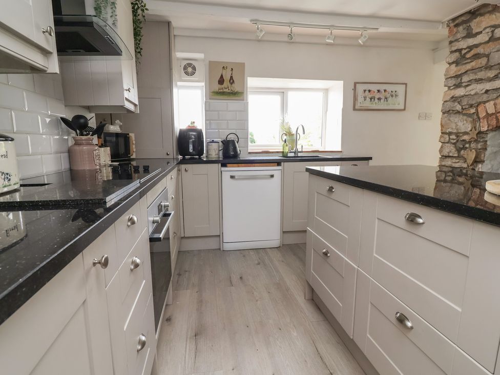 A kitchen with various appliances and cabinets at Tenandeleven Cottage Denbigh