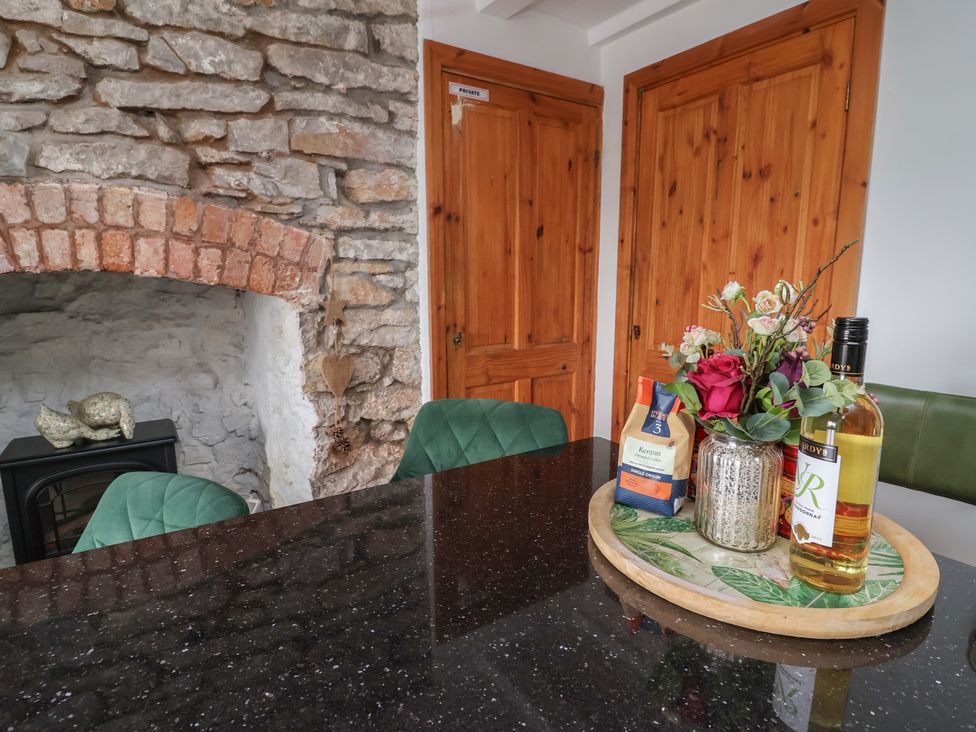 A kitchen with a stone fireplace and wooden furniture at Tenandeleven Cottage in Denbigh