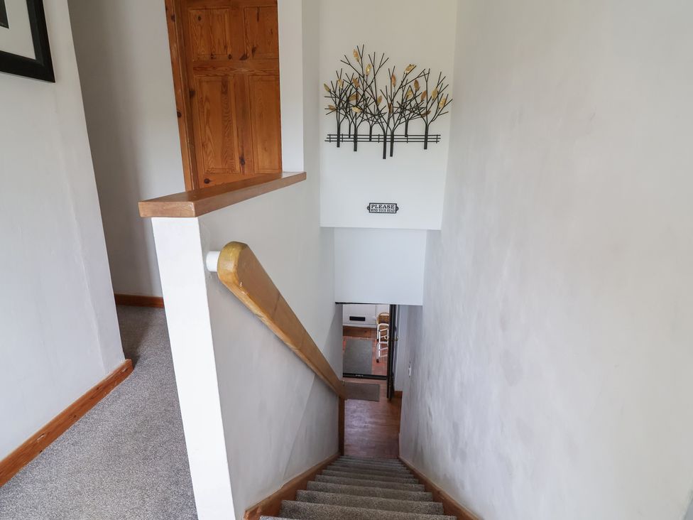A staircase with a handrail and wall art at Tenandeleven Cottage in Denbigh