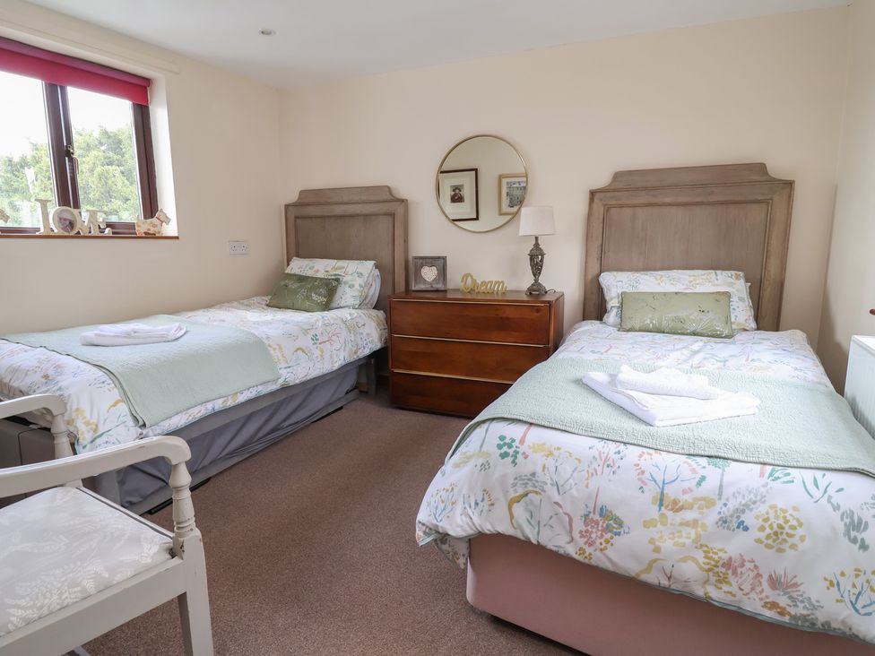 A bedroom with two beds and a dresser at Tenandeleven Cottage in Denbigh