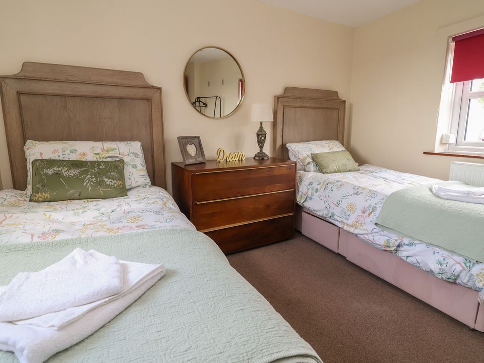 A bedroom with two beds and a dresser at Tenandeleven Cottage in Denbigh