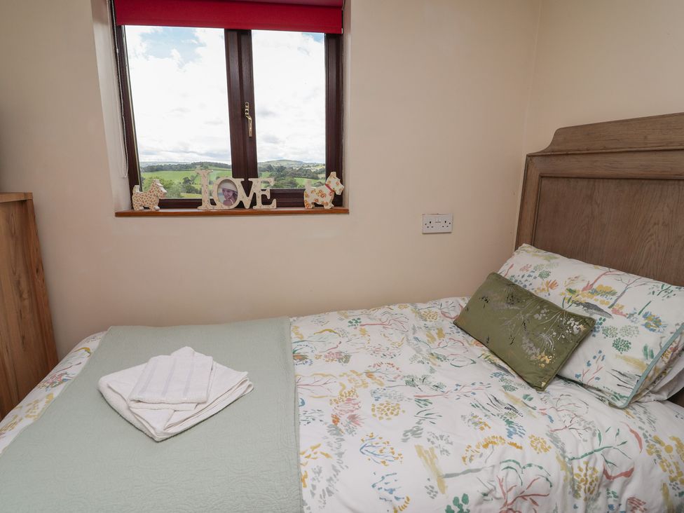 A bedroom with a bed and window at Tenandeleven Cottage Denbigh