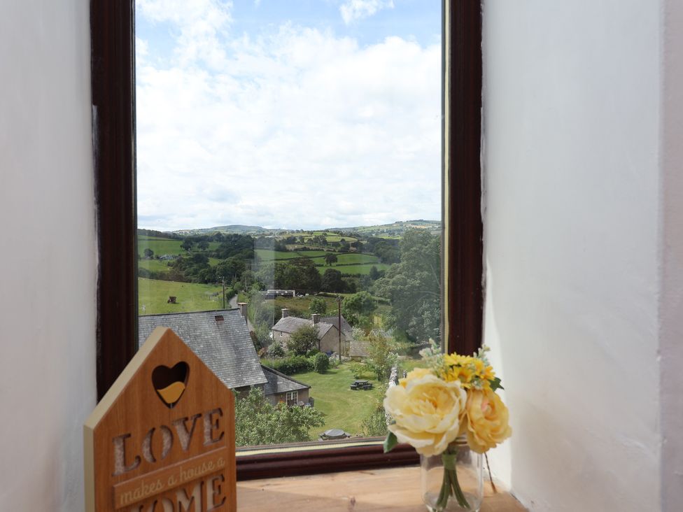 A window with flowers and a sign at Tenandeleven Cottage in Denbigh