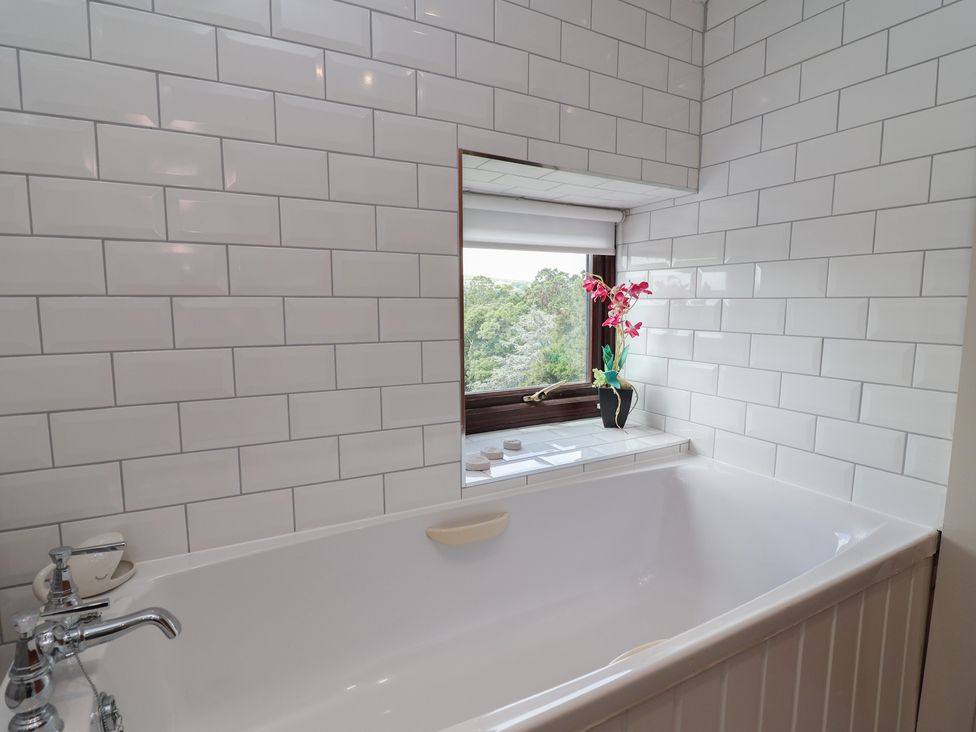 A bathroom with a bathtub and a window at Tenandeleven Cottage in Denbigh