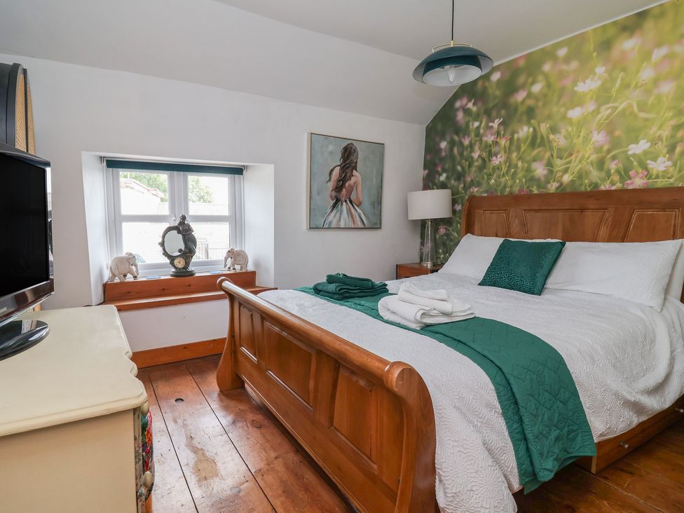 A bedroom with a bed and television at Tenandeleven Cottage Denbigh