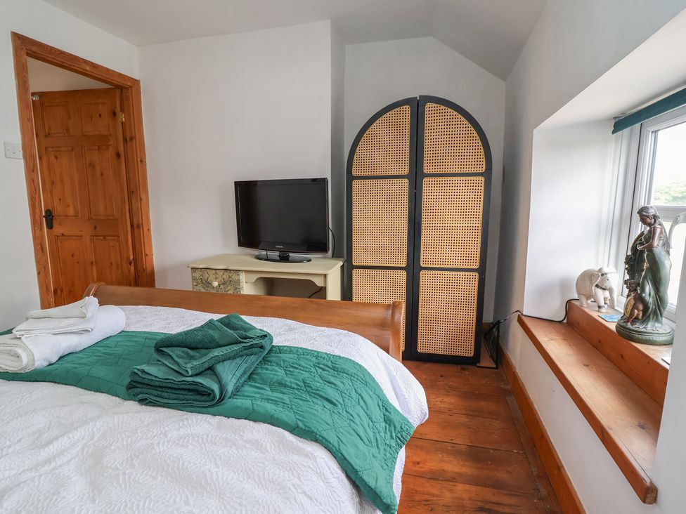 A bedroom with a bed and television at Tenandeleven Cottage Denbigh