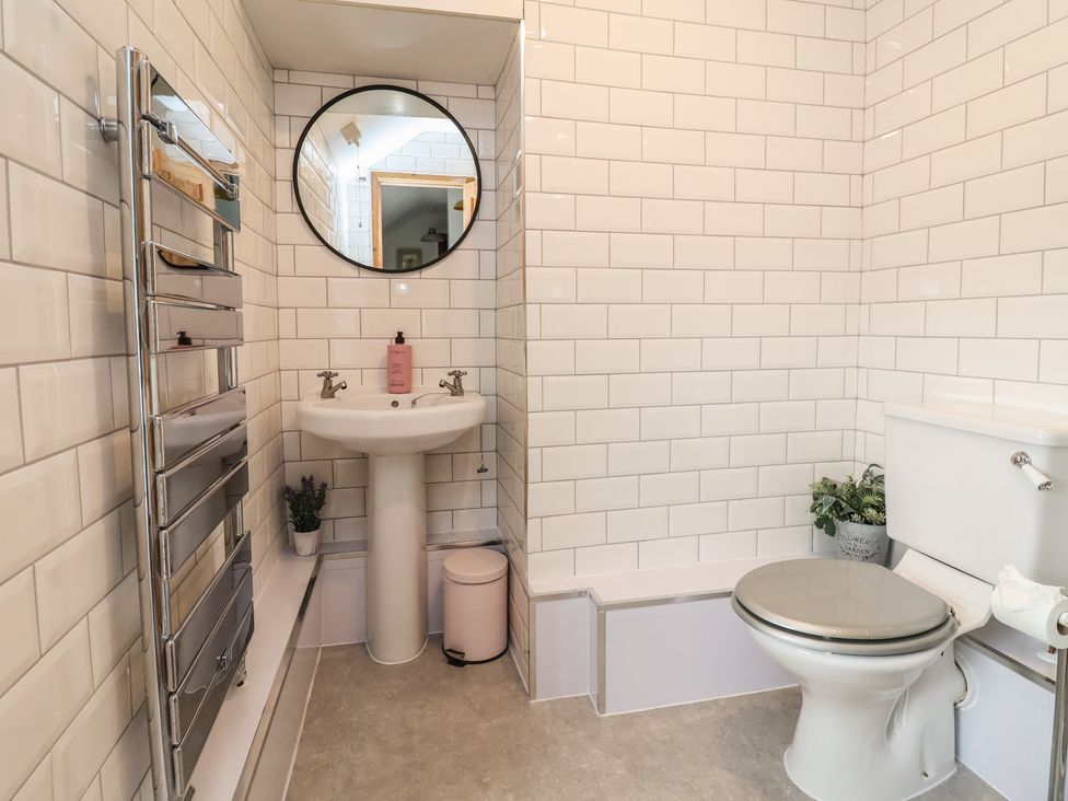A bathroom with a sink, toilet, and towel radiator at Tenandeleven Cottage in Denbigh