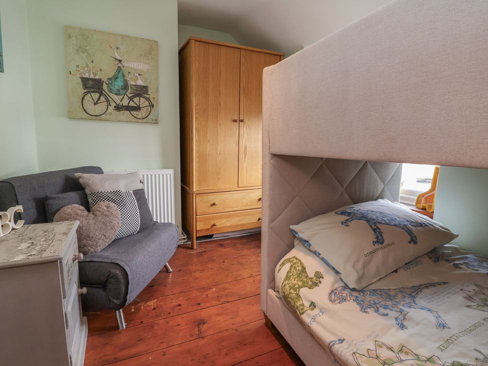 A bedroom with a bed and a sofa at Tenandeleven Cottage in Denbigh