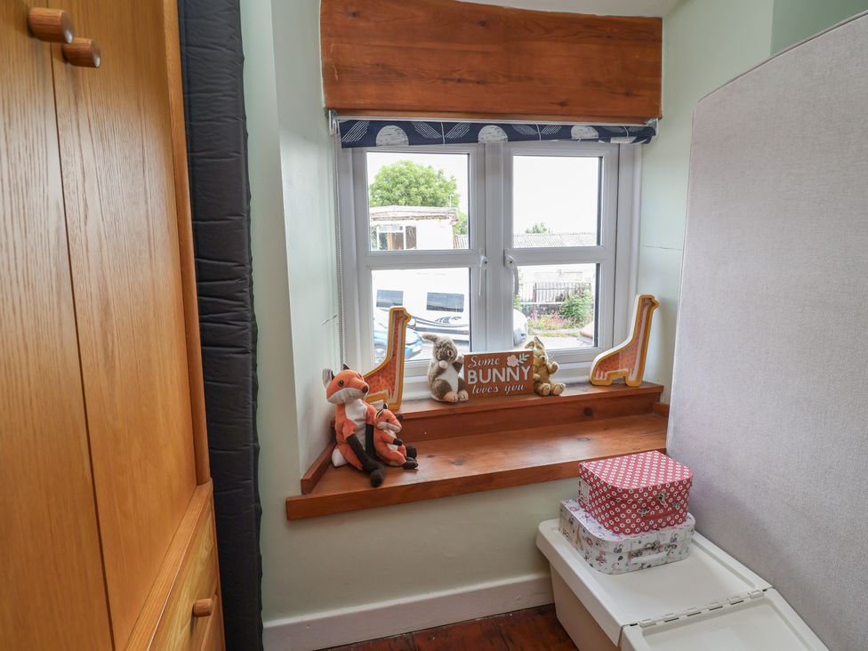 A bedroom with a window and toys on a shelf at Tenandeleven Cottage Denbigh