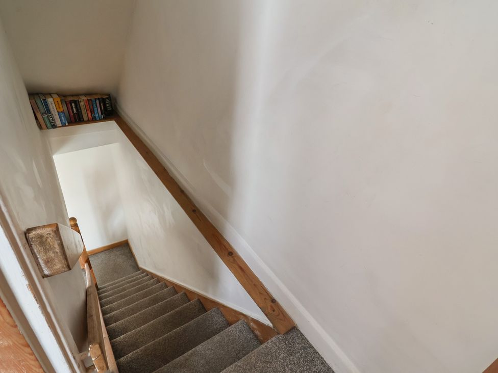 A staircase with a bookshelf and a handrail at Tenandeleven Cottage Denbigh