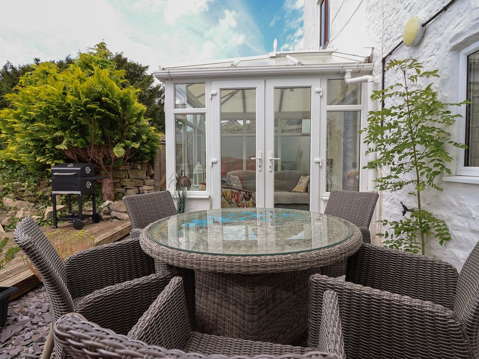 A dining set with a grill in a garden at Tenandeleven Cottage in Denbigh