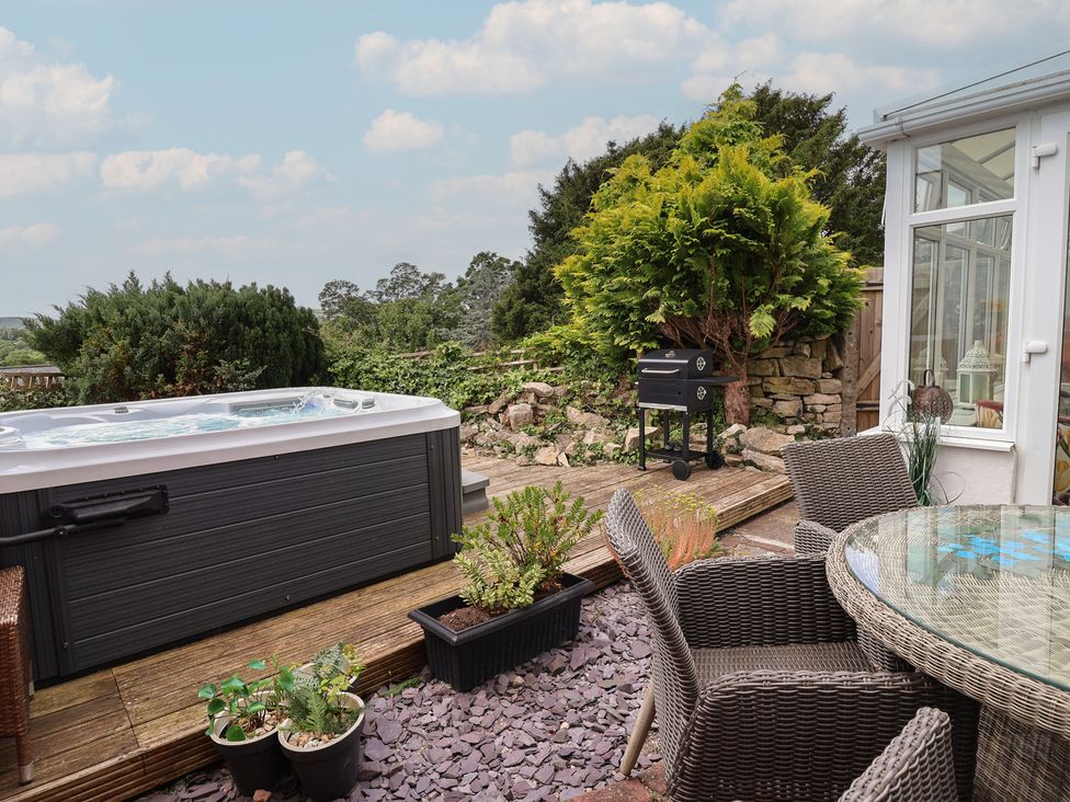 An outdoor area with a hot tub and grill at Tenandeleven Cottage in Denbigh