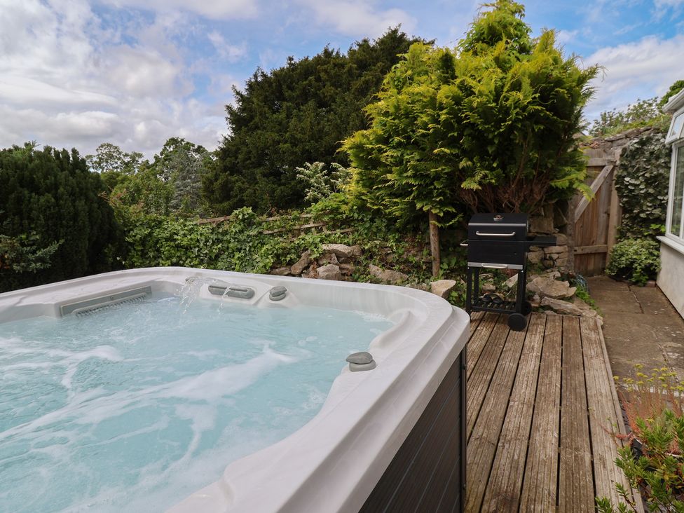 An outdoor area with a hot tub and barbecue grill at Tenandeleven Cottage in Denbigh