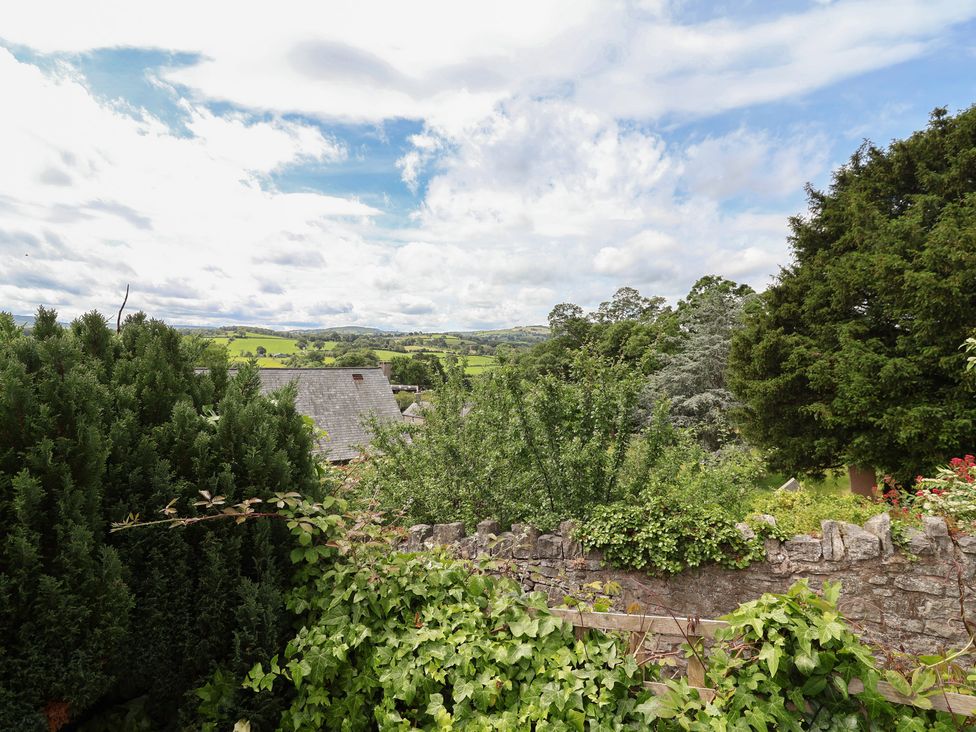 A view of hills and greenery from a stone wall at Tenandeleven Cottage in Denbigh