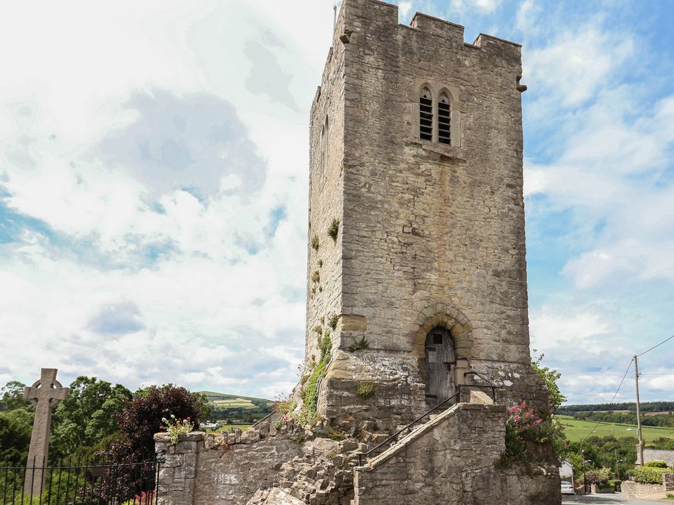 A stone tower structure with stairs and grass at Tenandeleven Cottage, Denbigh