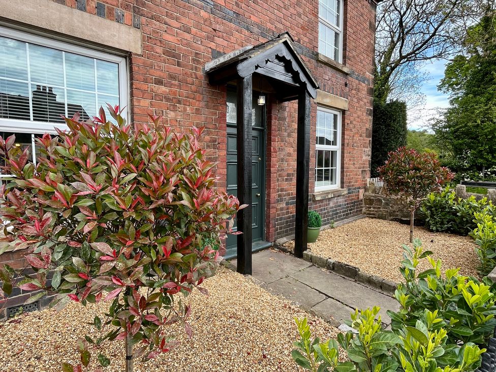 An entrance with a brick wall and plants at Horseshoe Cottage in Macclesfield