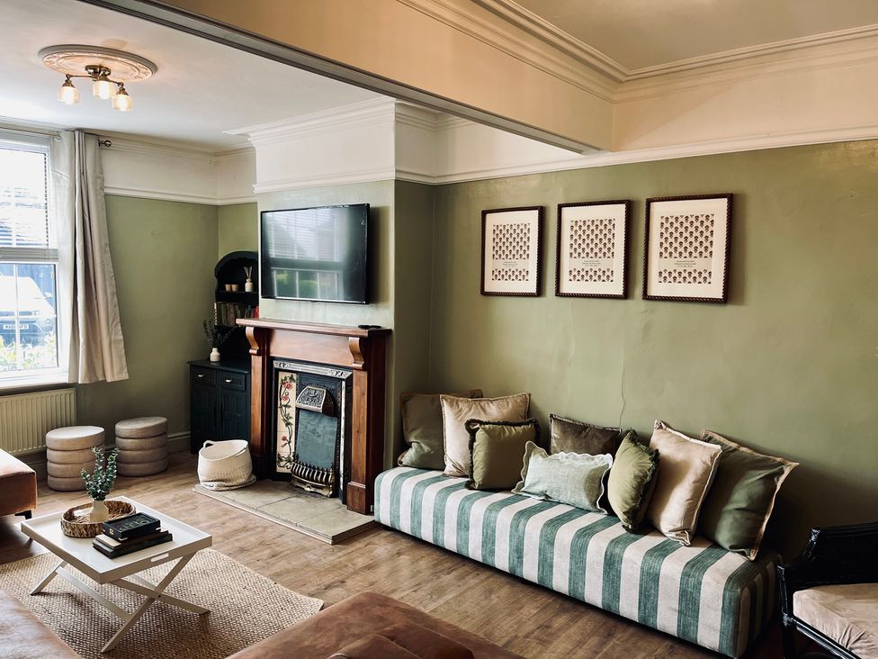A living room with a sofa and a television at Horseshoe Cottage in Macclesfield