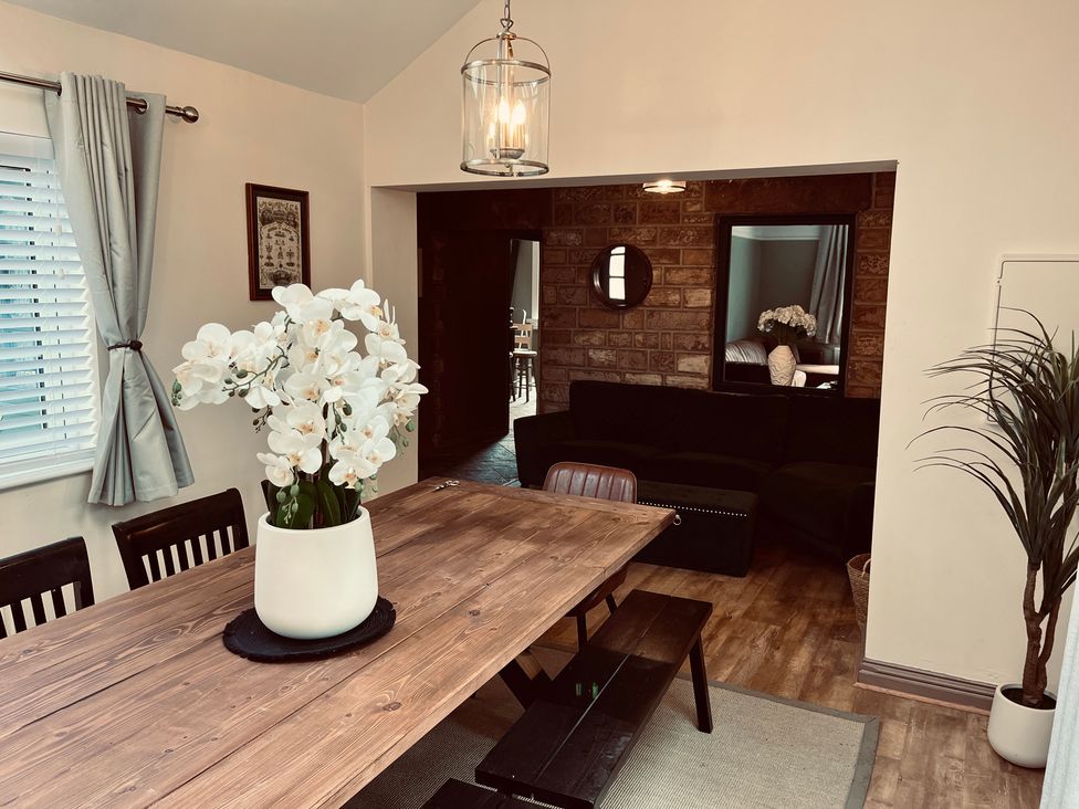 A dining room with a wooden table and chairs at Horseshoe Cottage in Macclesfield