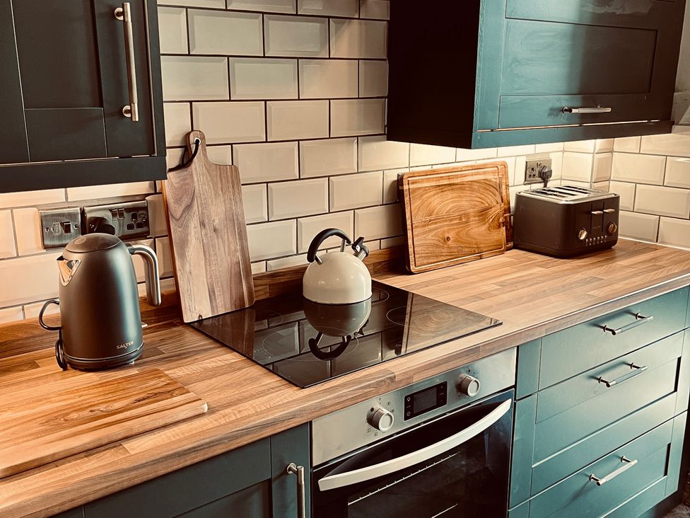 A kitchen with a kettle, toaster, and cutting board at Horseshoe Cottage in Macclesfield