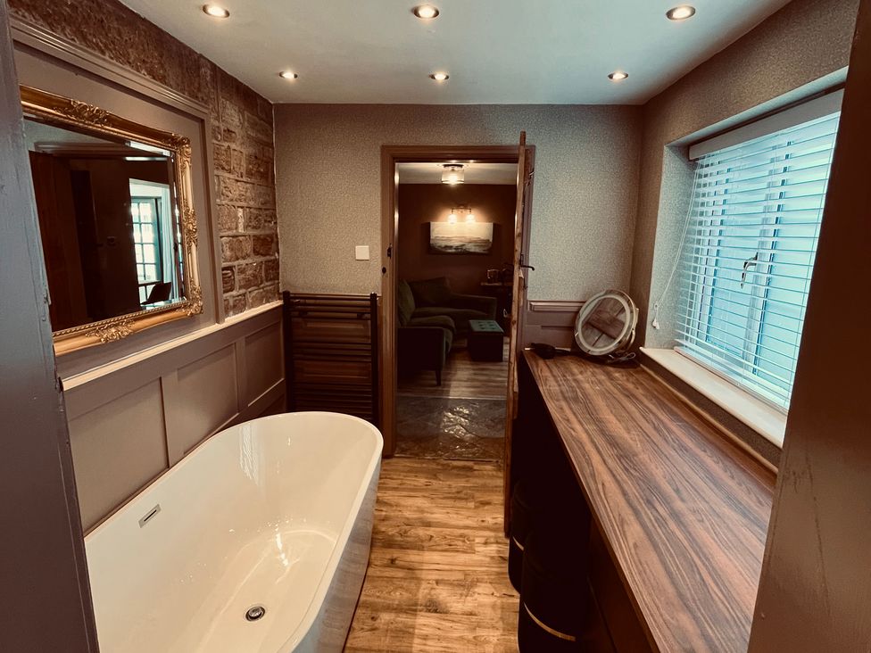 A bathroom with a bathtub and window at Horseshoe Cottage in Macclesfield