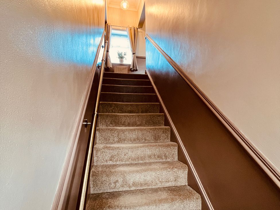 A staircase with a handrail and curtains at Horseshoe Cottage in Macclesfield