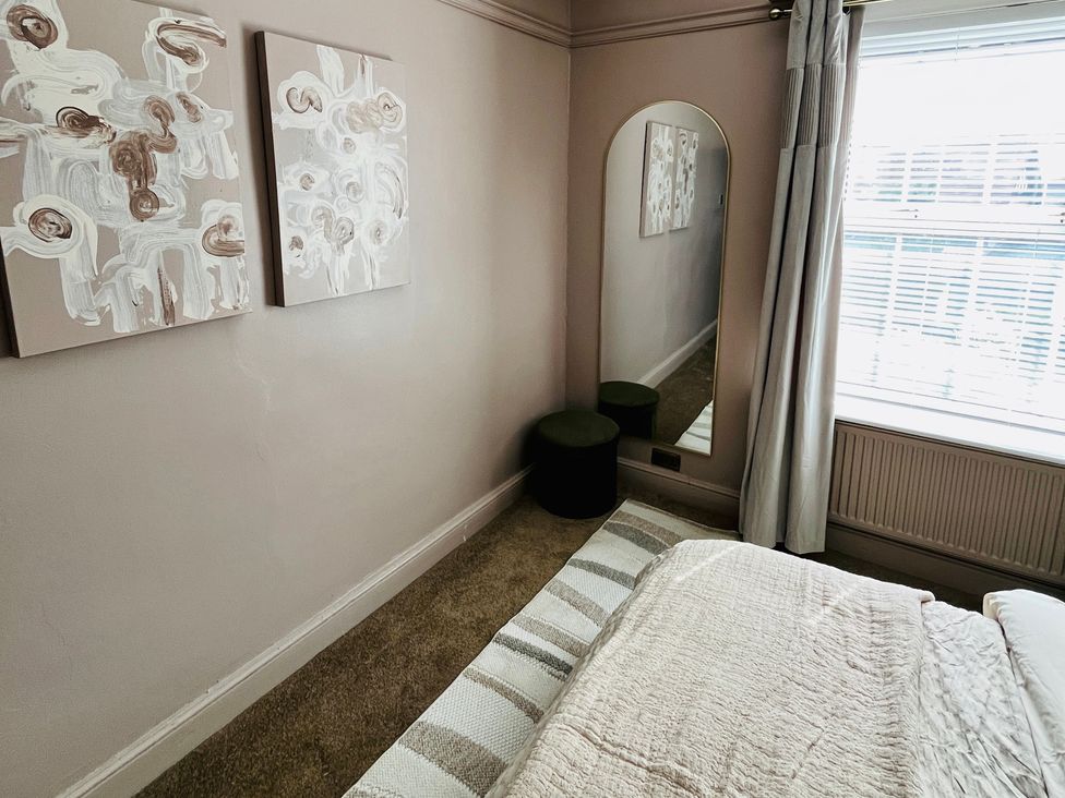 A bedroom with a mirror and paintings at Horseshoe Cottage in Macclesfield