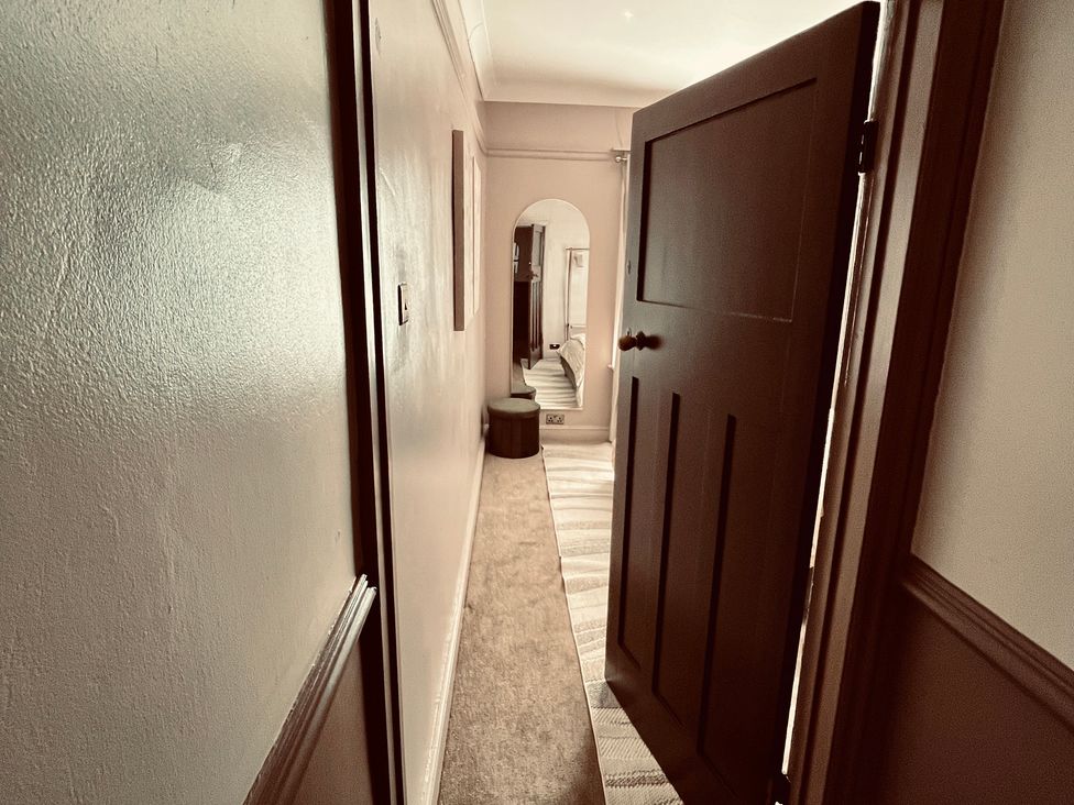 A hallway with a door and mirror at Horseshoe Cottage in Macclesfield
