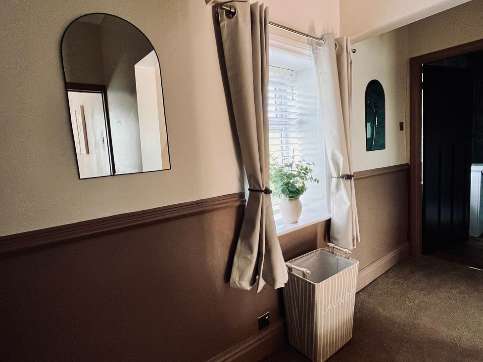 A hallway with a window and laundry basket at Horseshoe Cottage in Macclesfield