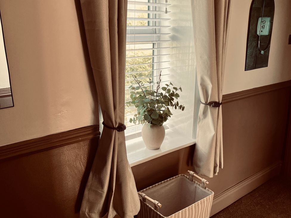 A living room with a window and a plant on the sill at Horseshoe Cottage in Macclesfield